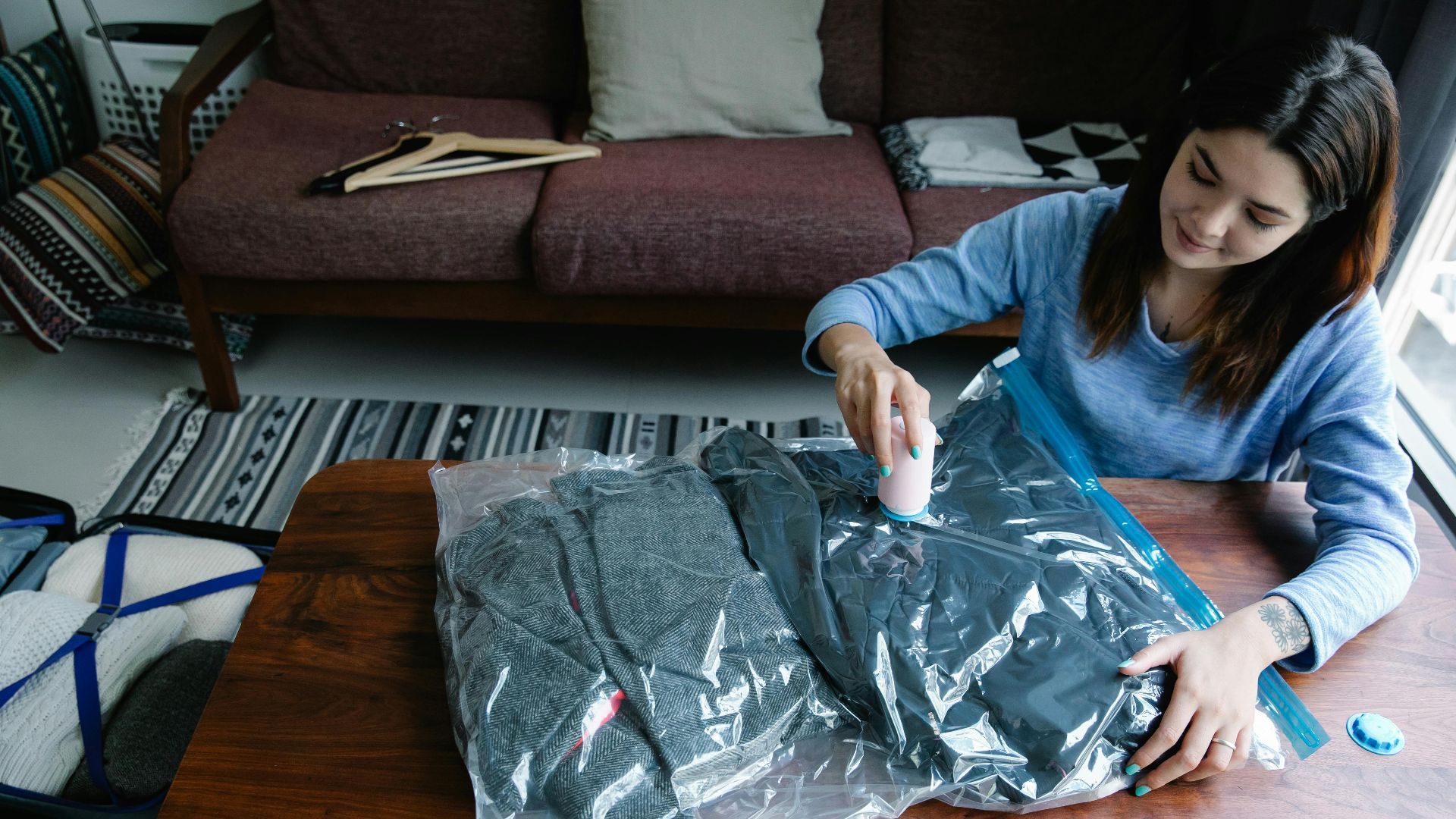 Woman sealing clothes in vacuum bags for efficient packing at home.