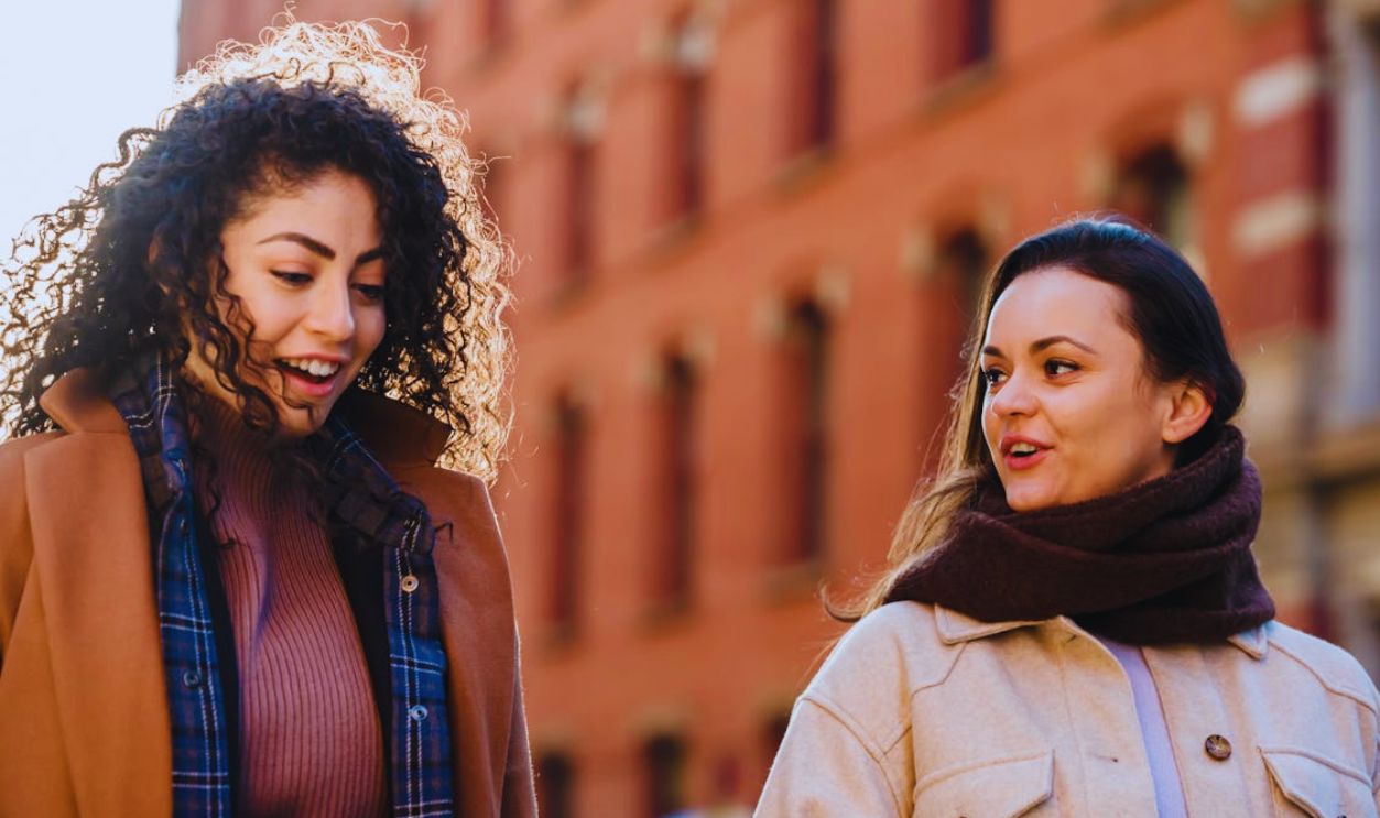Happy diverse females strolling on street and chatting
