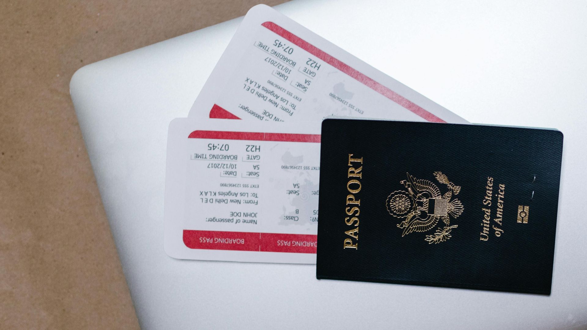 Close-up of a passport and boarding passes on a laptop, symbolizing travel preparation.