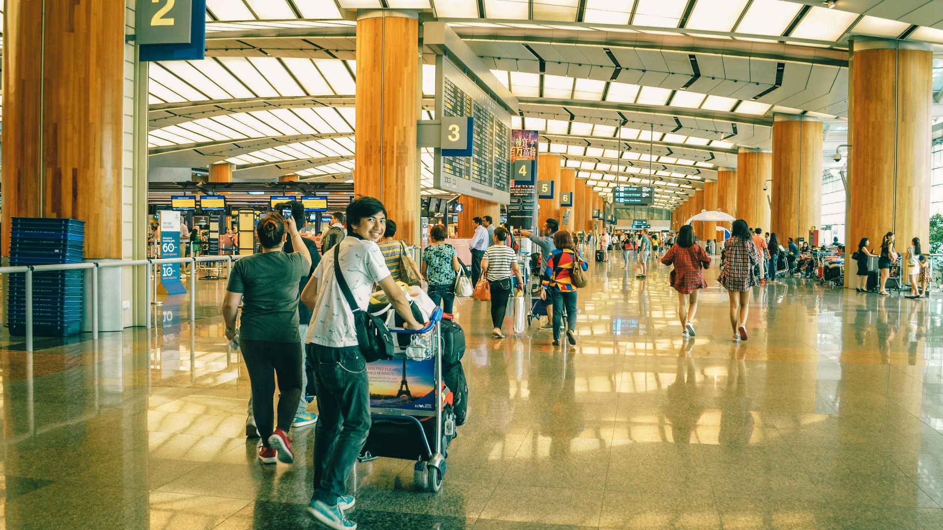 Travelers bustling through Singapore Changi Airport terminal, highlighting the dynamic and vibrant atmosphere of international travel.