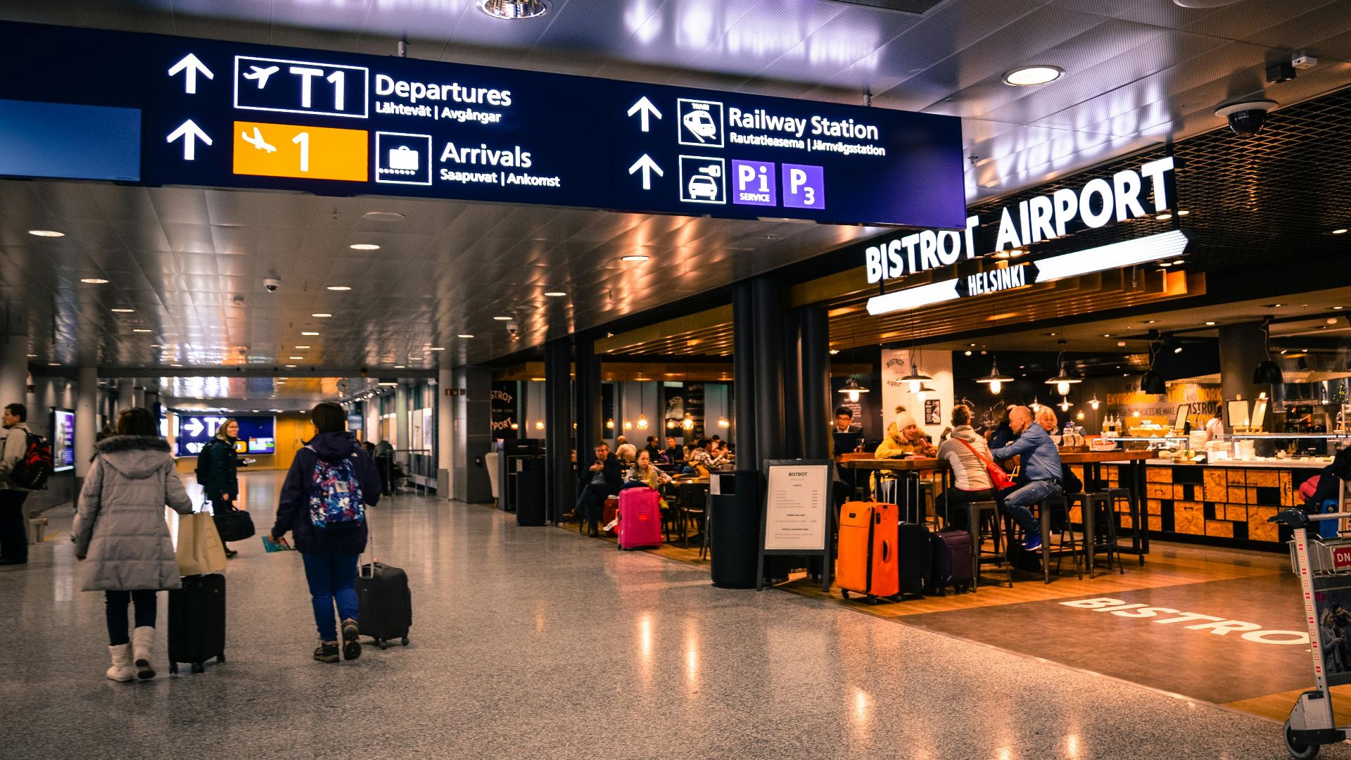 Travelers at Helsinki Airport dining and shopping near departures and arrivals.