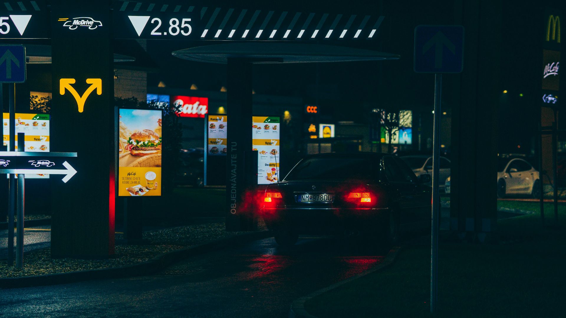 Car navigating a McDonald's drive-thru at night, showcasing urban dining atmosphere.
