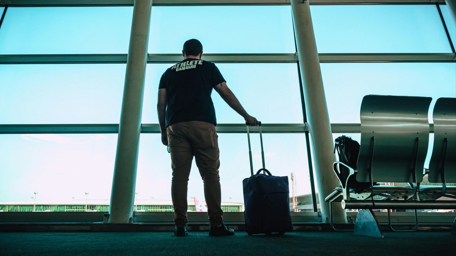 Man with luggage waiting at airport lounge, anticipating departure in a modern setting.