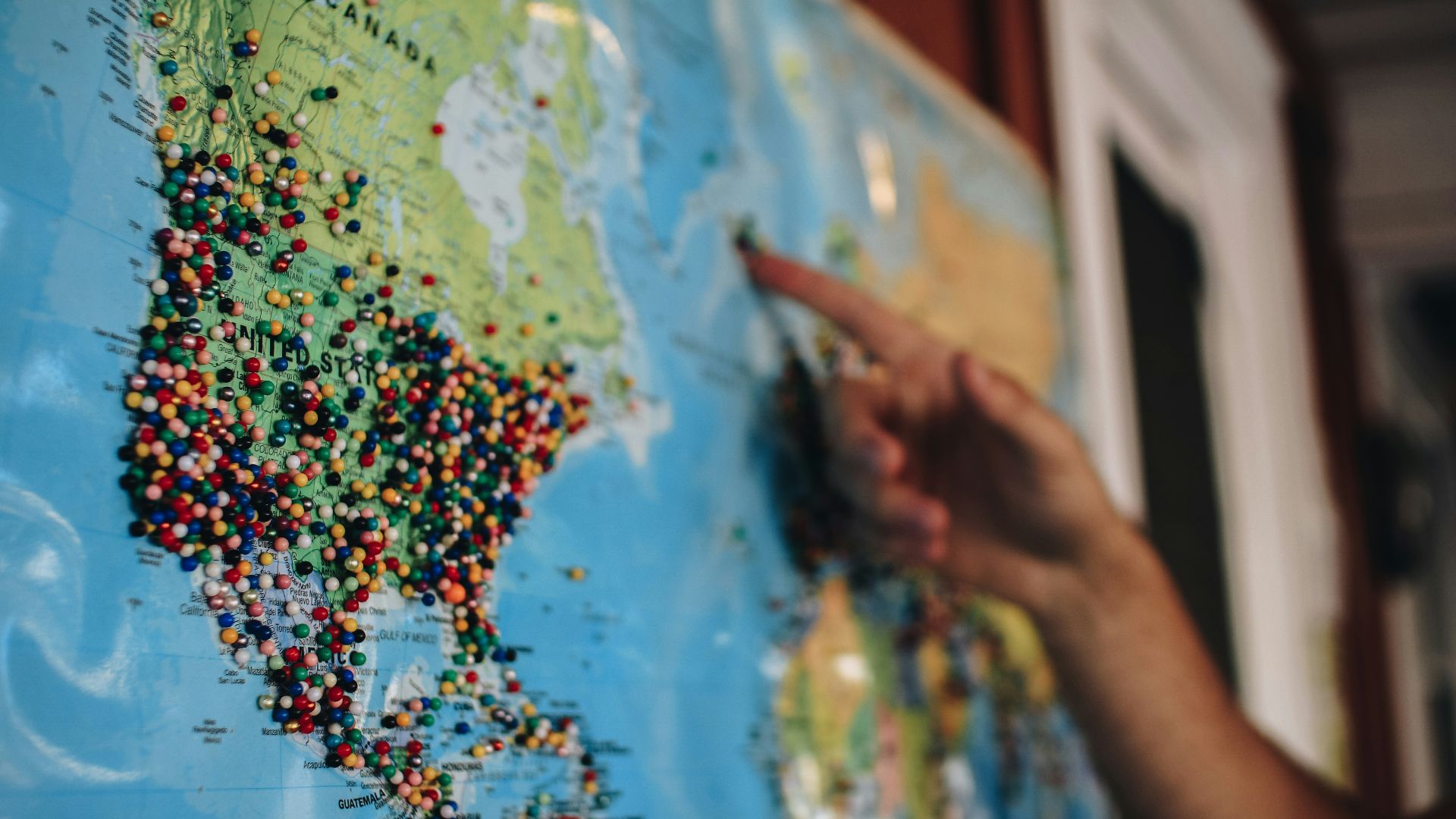 a person pointing at a map with pins on it