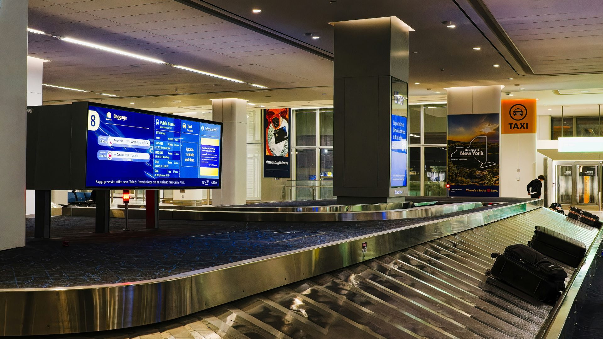 a luggage carousel in an airport with a large screen
