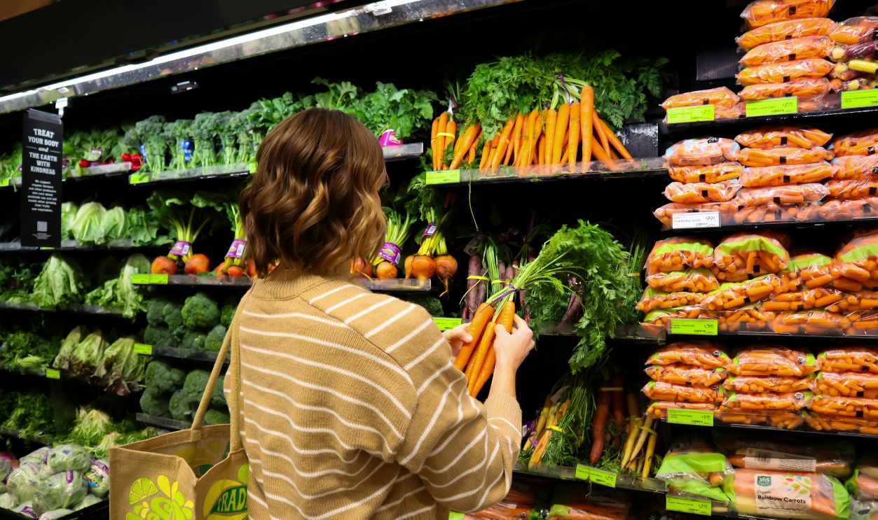 Back View of Woman Choosing Carrots at Supermarket