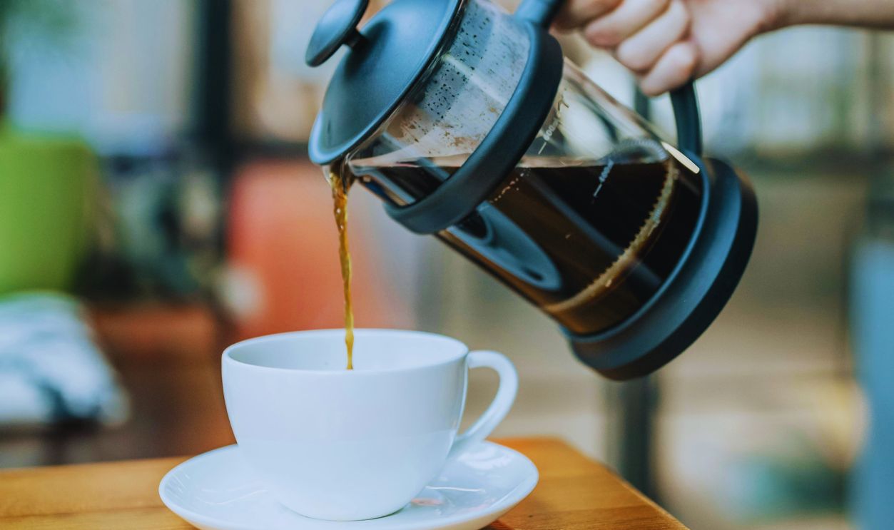 A Person Pouring Coffee on a Ceramic Cup