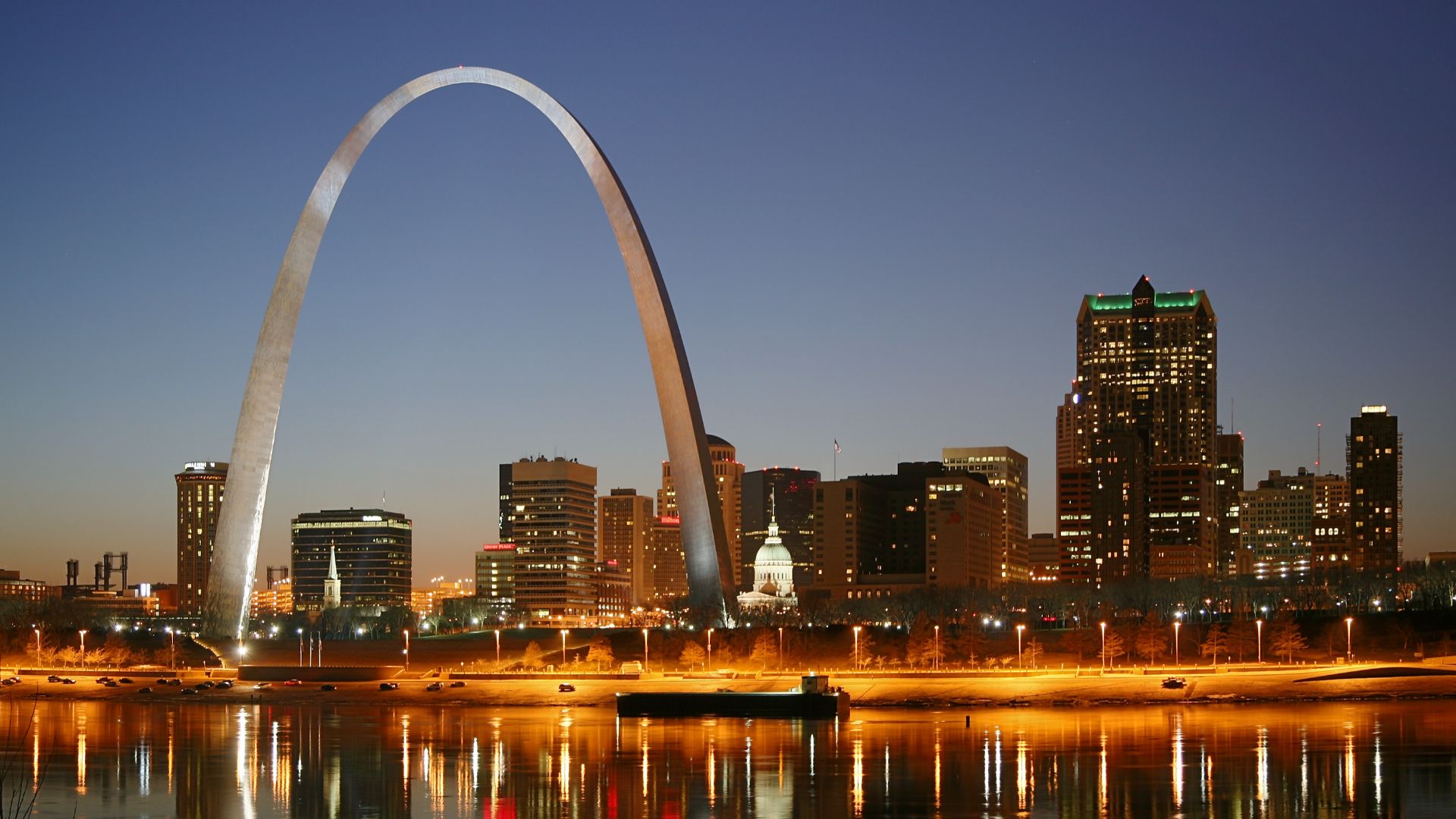 St. Louis on the Mississippi river by night. Jefferson National Expansion Memorial aka. Gateway Arch and Old Courthouse are visible.