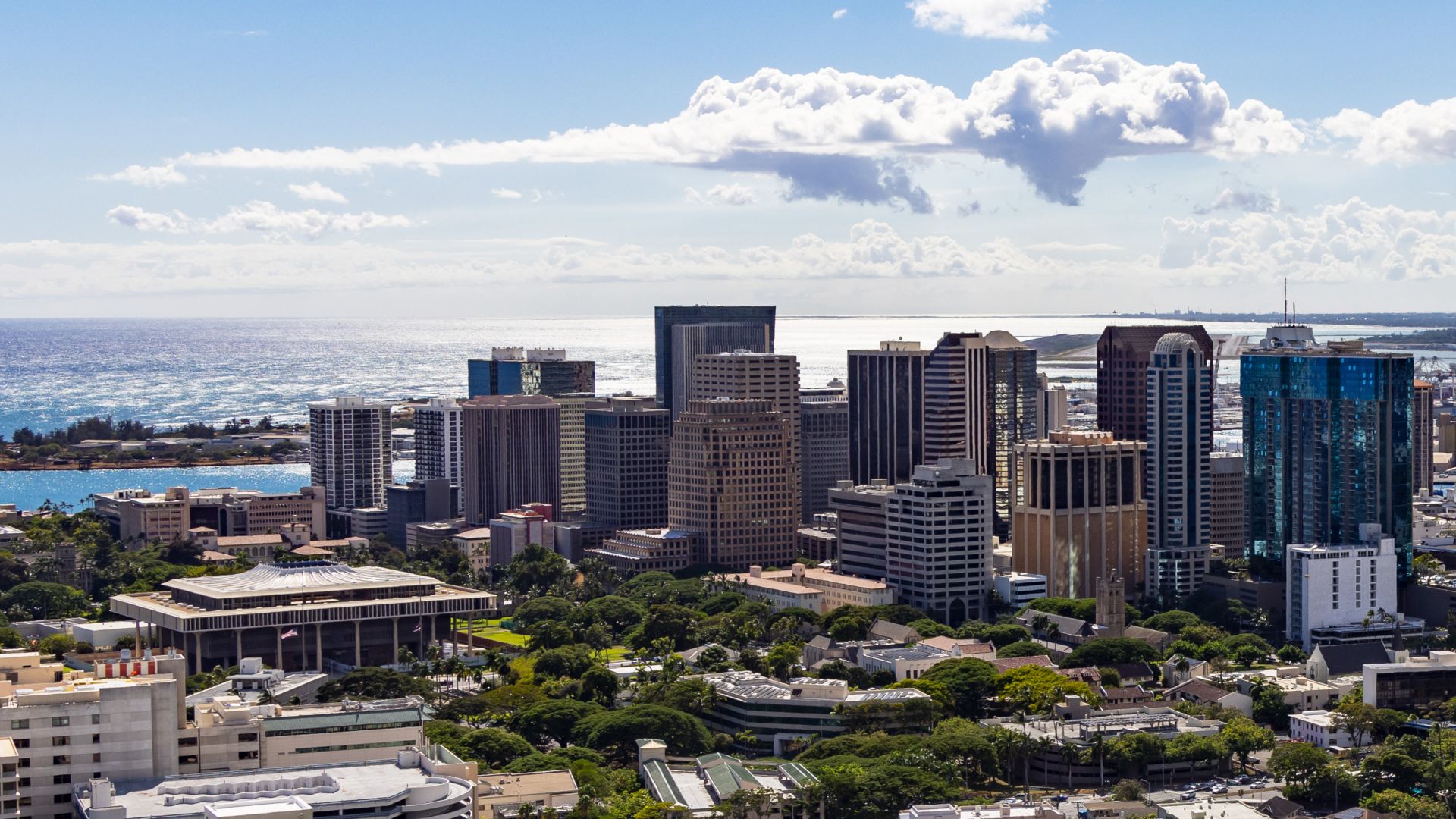 Picture of Downtown Honolulu taken at Pūowaina/Punchbowl Crater/National Memorial Cemetery of the Pacific, showing Downtown Honolulu and the Hawaii State Capitol, with the Reef Runway/Daniel K. Inouye International Airport in the background.