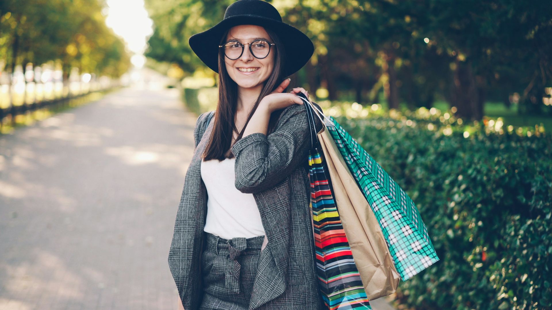 Young woman with shopping bags in a park.