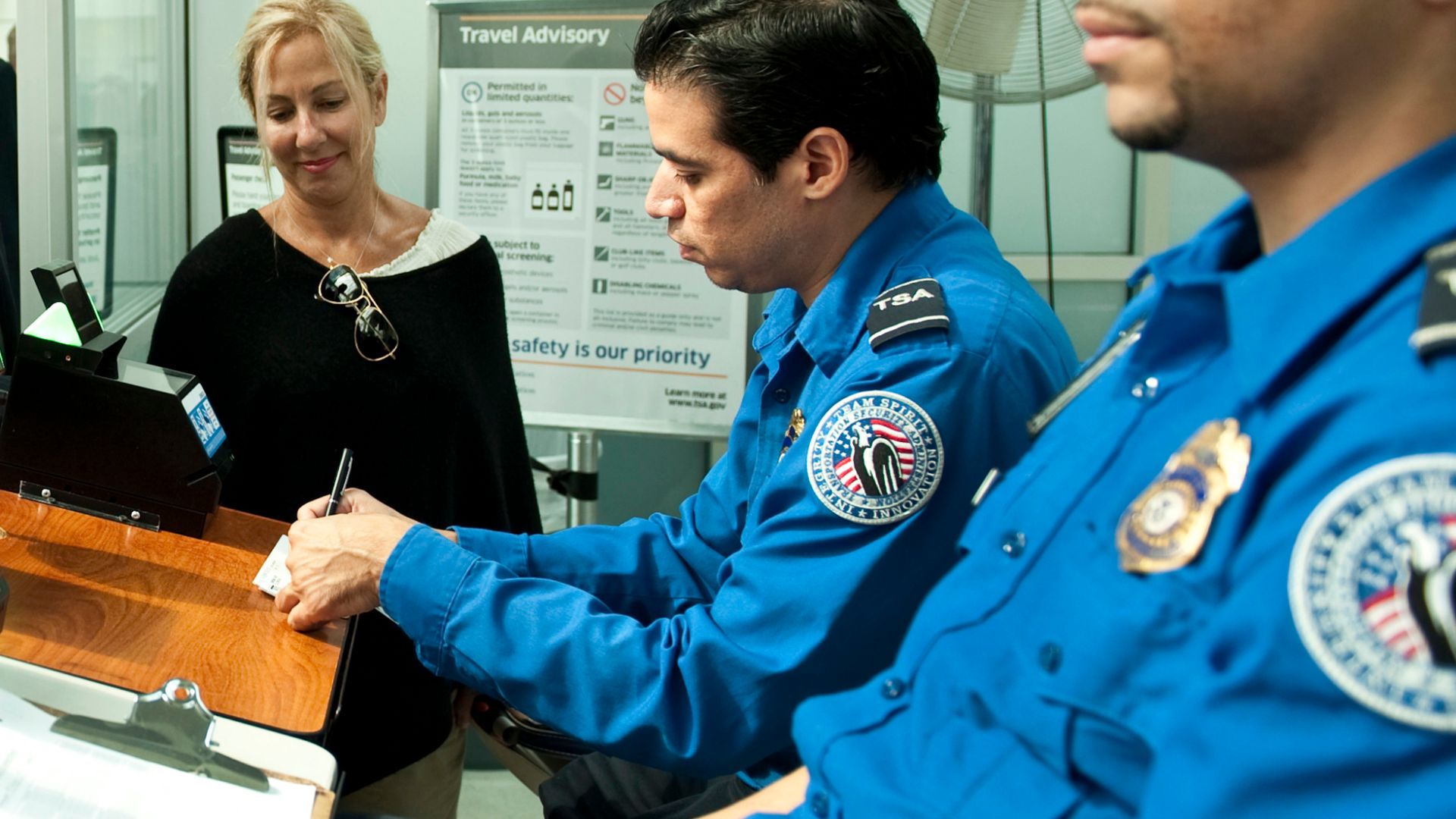 NEW YORK - Dr. Susan DiMarco, center, observes a Transportation Security Administration agent verify her boarding pass ahead of her husband Secretary of Homeland Security Jeh Johnson, left, at John F. Kennedy International Airport in Queens on Sept. 11, 2014. A component of DHS, TSA’s primary mission is to protect the Nation's transportation systems to ensure freedom of movement for people and commerce. Official DHS photo by Barry Bahler.