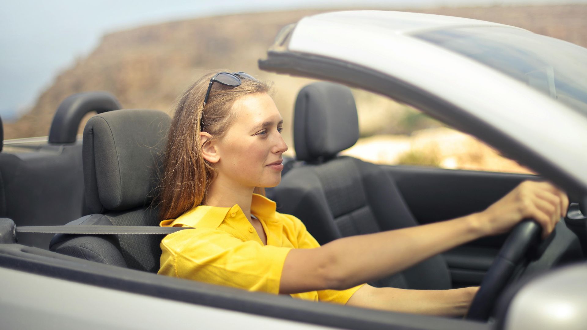 A young woman enjoys driving a convertible on a sunny day in Malta.