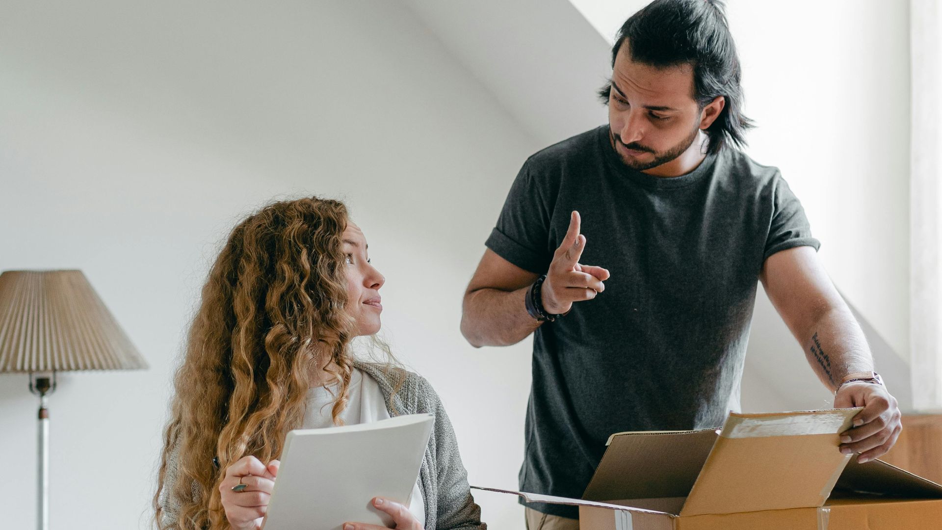 A couple organizing belongings in their room, planning a move with a checklist.