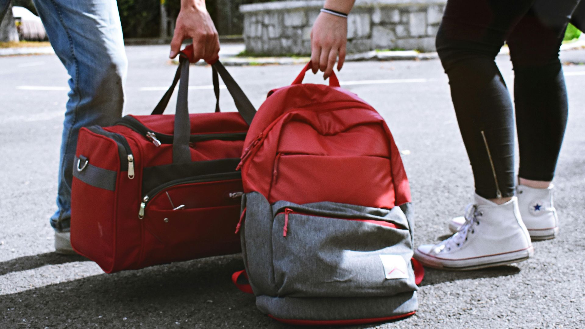 Two travelers holding red bags on a street, symbolizing travel and exploration.