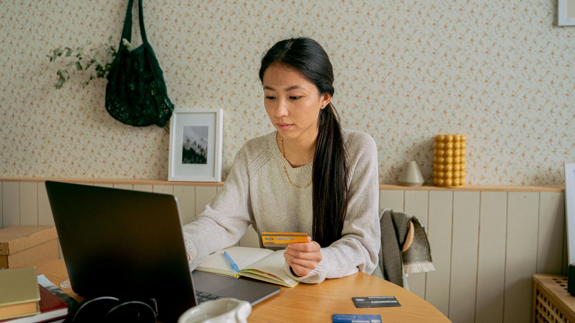 A woman using a laptop and credit card for online shopping at a cozy indoor setting.