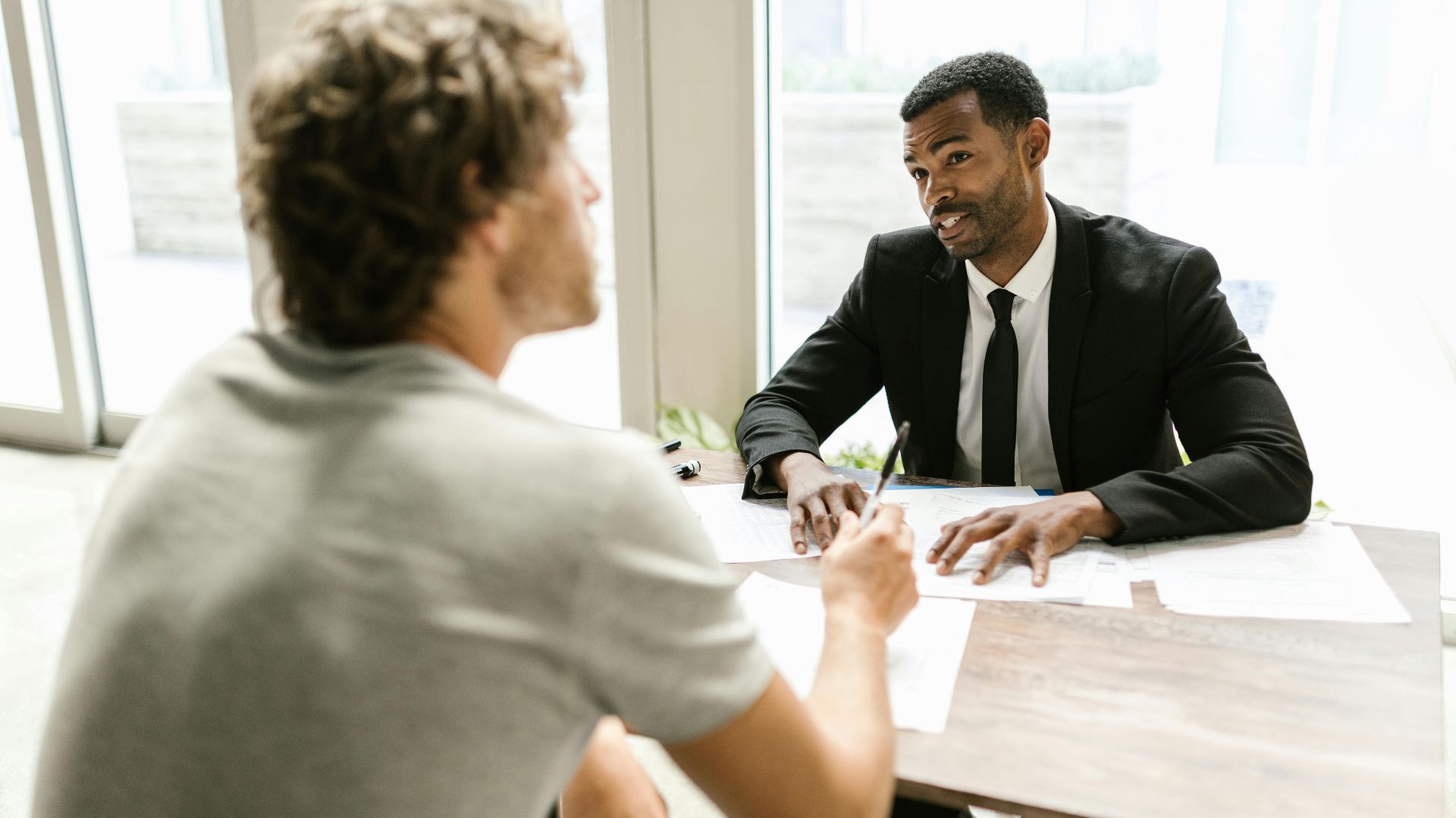 Two men having a discussion over documents in a modern office setting.
