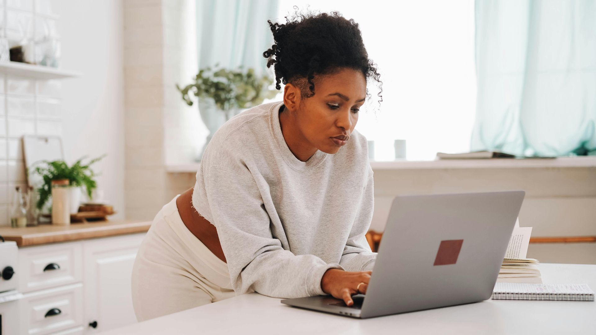 A woman using a laptop in a cozy home setting, focused on online education.