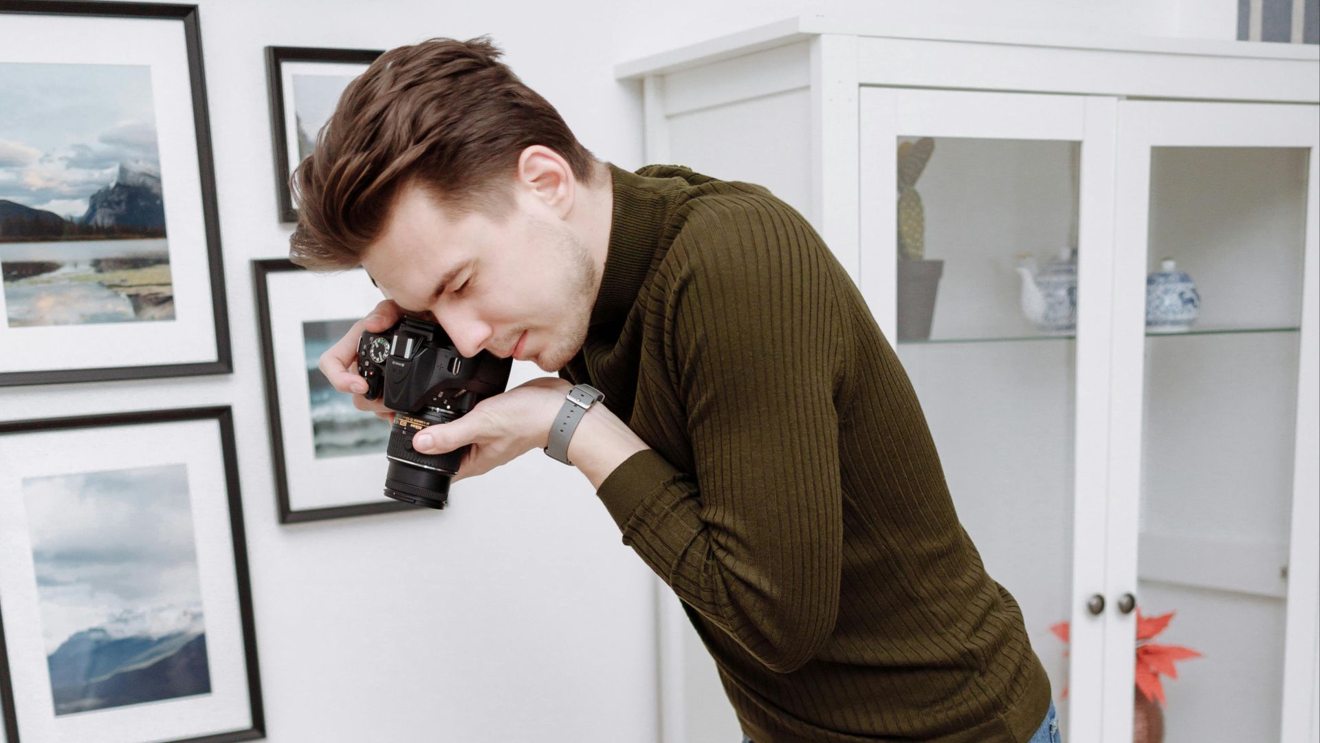 A photographer creatively captures a flat lay of clothing on the floor in a modern room.