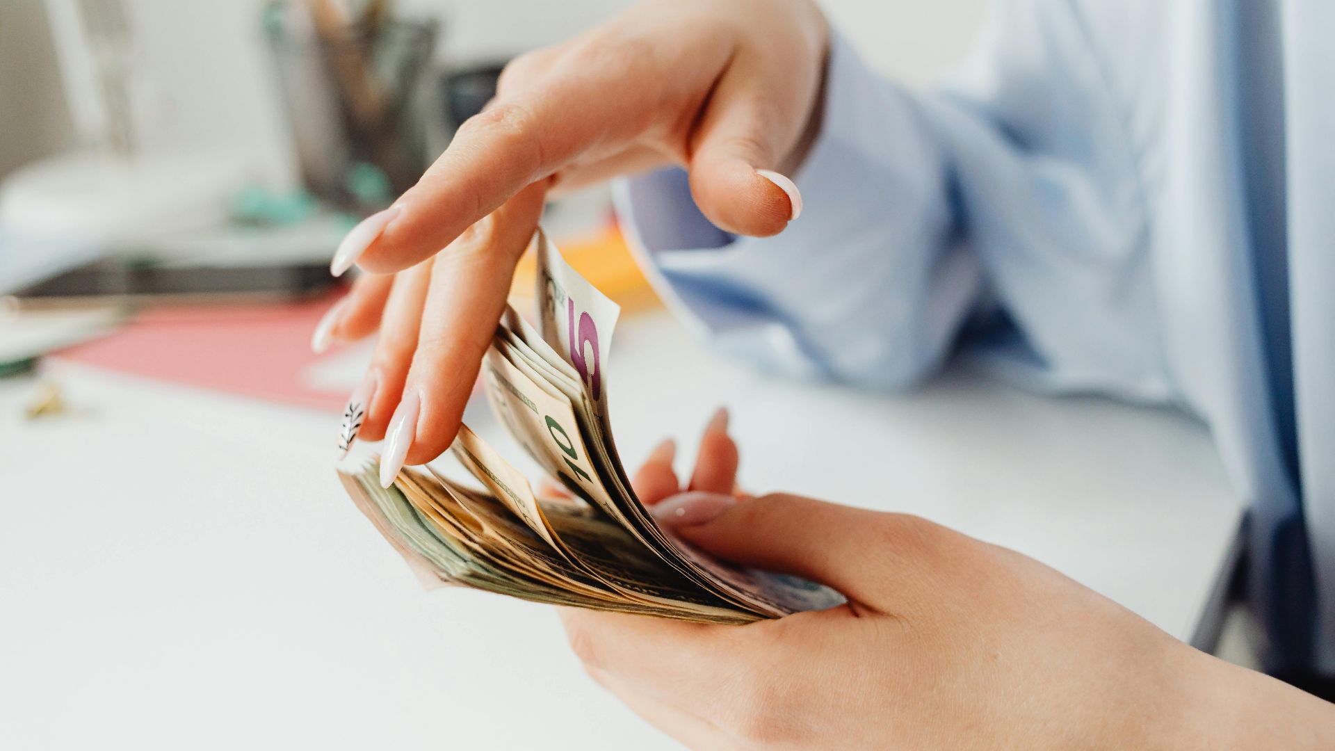 Close-up of a woman's hand counting euro banknotes on the office desk.