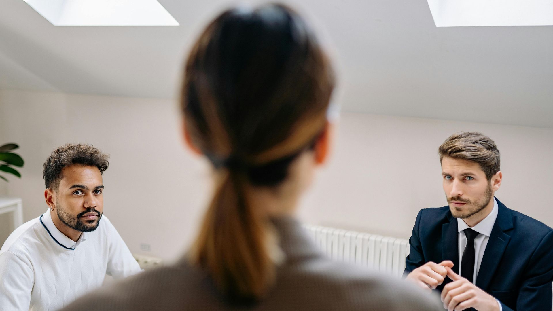 A professional business meeting involving three adults in a modern office setting.
