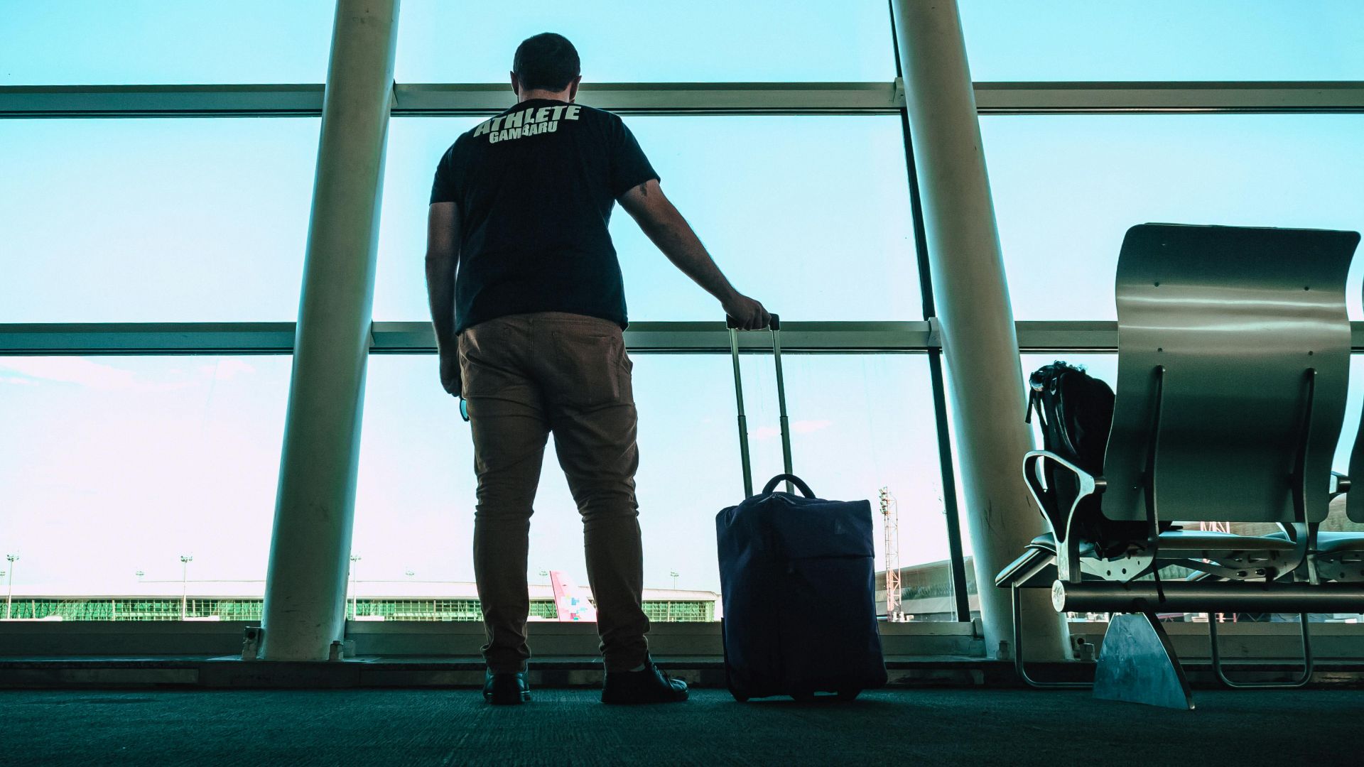 Man with luggage waiting at airport lounge, anticipating departure in a modern setting.