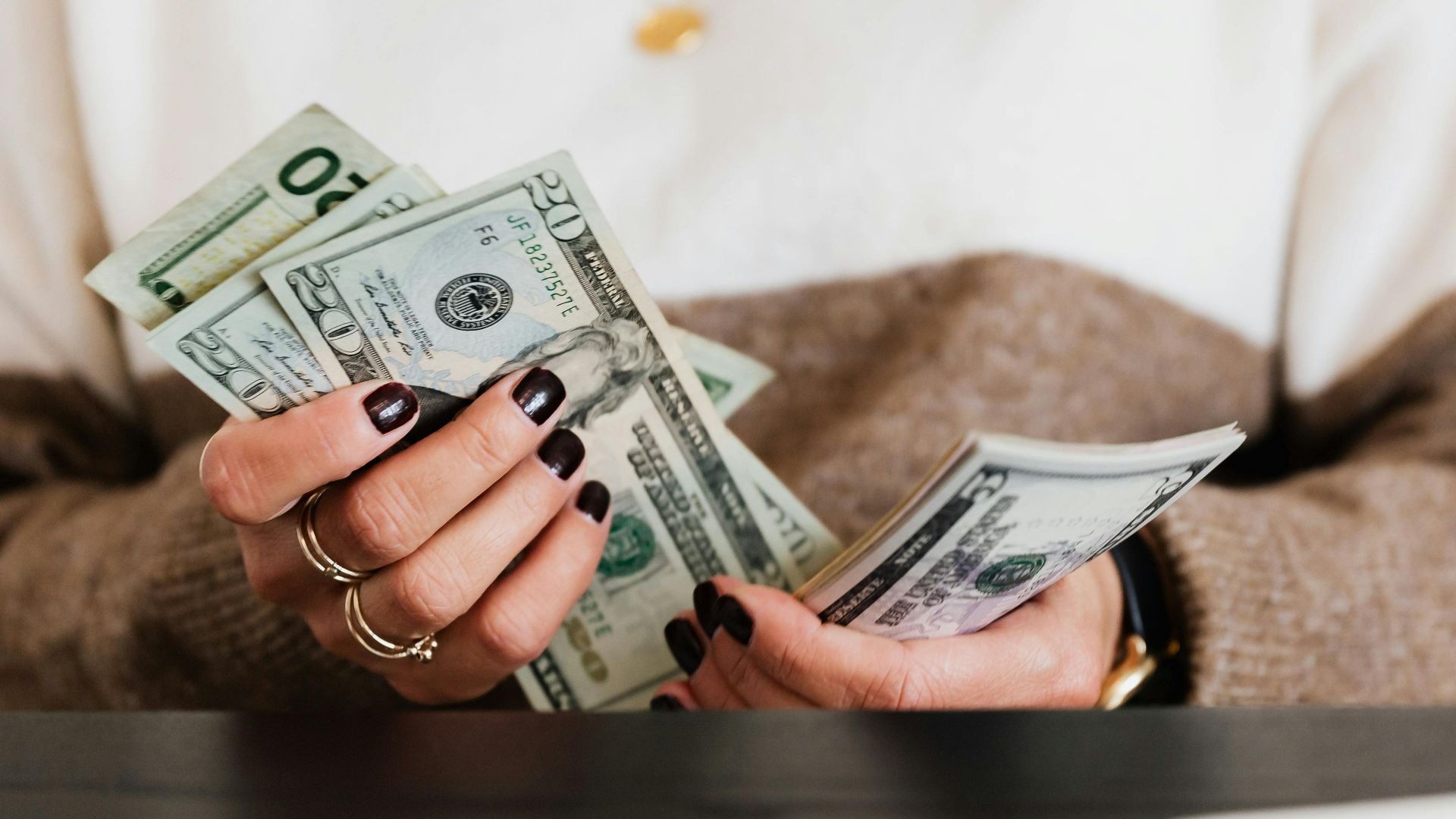 Close-up of hands counting US dollar bills, depicting finance and money handling.