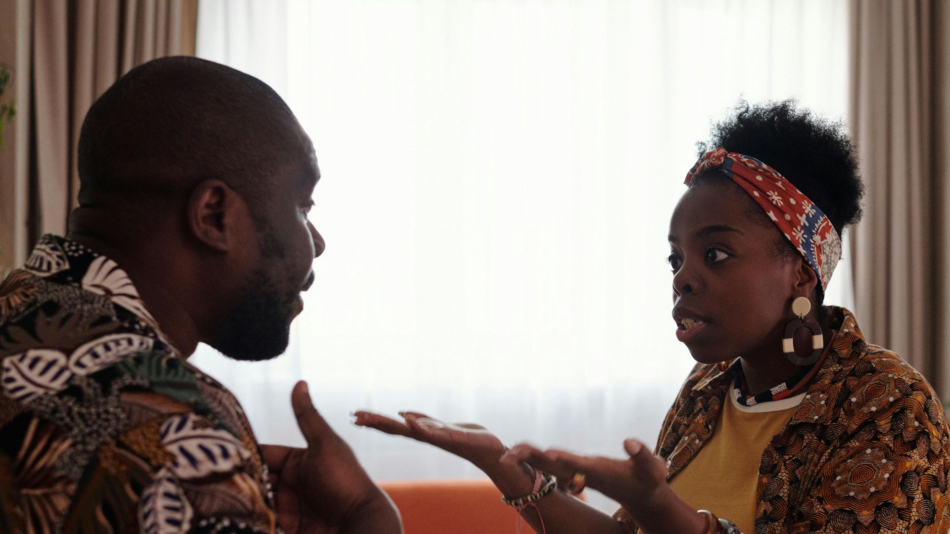 A couple arguing passionately in their living room, expressing emotions and gestures.