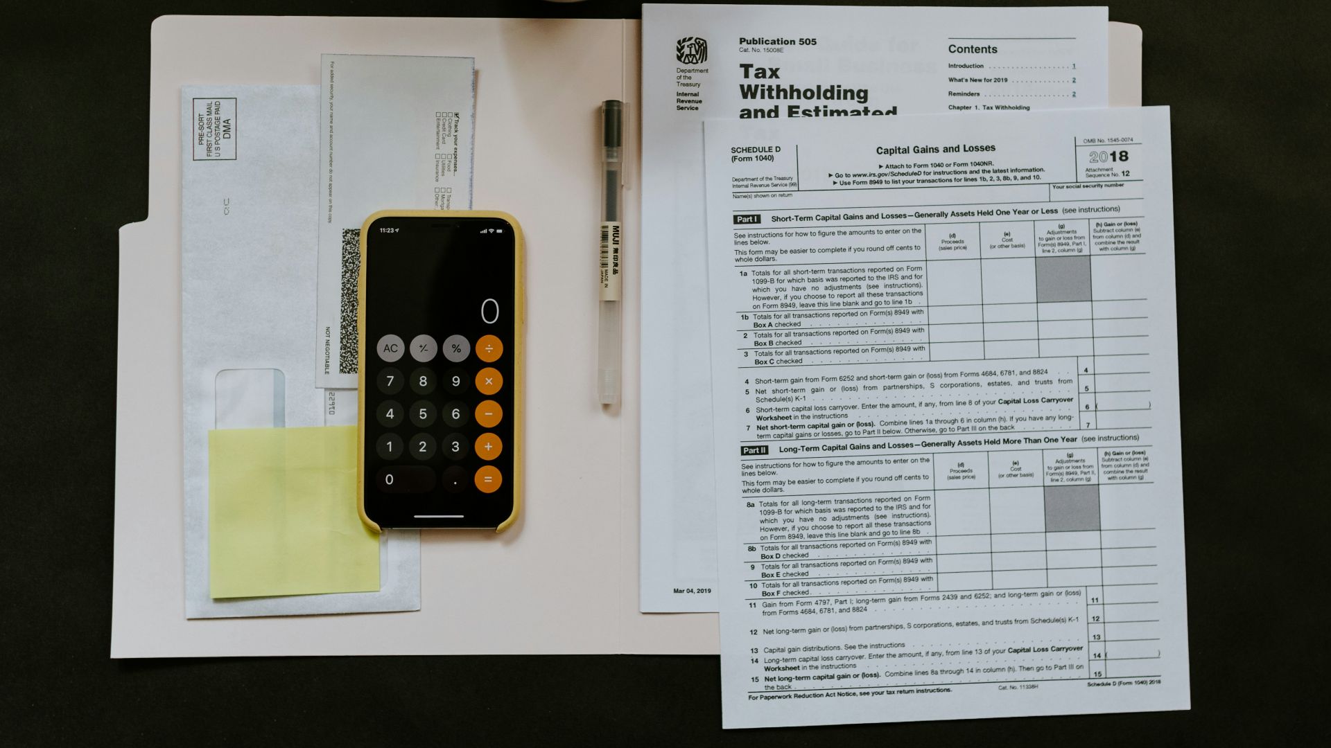 black Android smartphone near ballpoint pen, tax withholding certificate on top of white folder