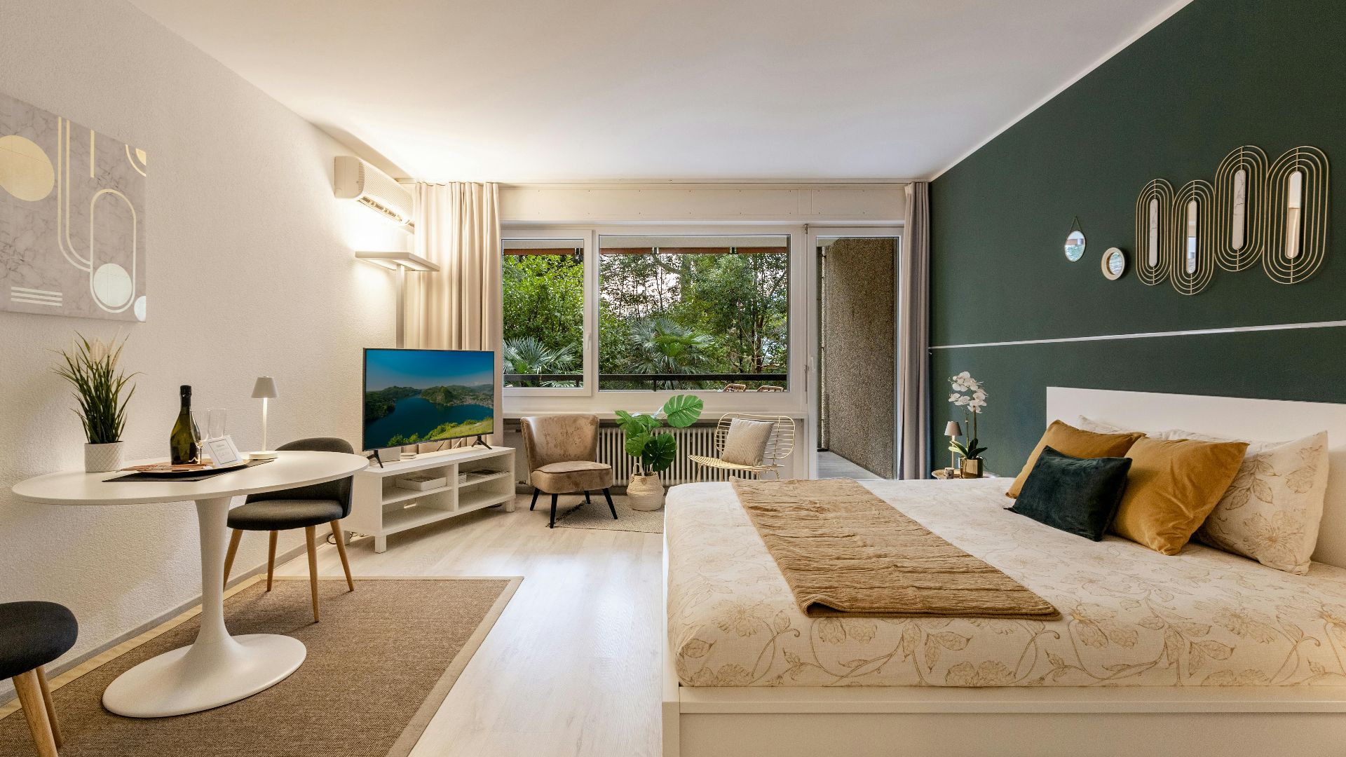 Stylish studio apartment featuring modern decor, green accent wall, and large windows.