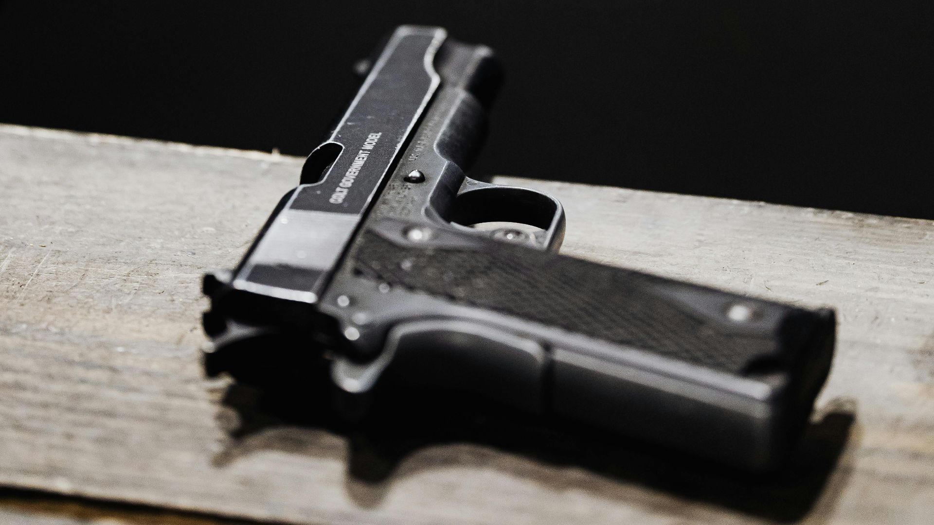 Detailed shot of a pistol placed on a wooden surface in an indoor setting.