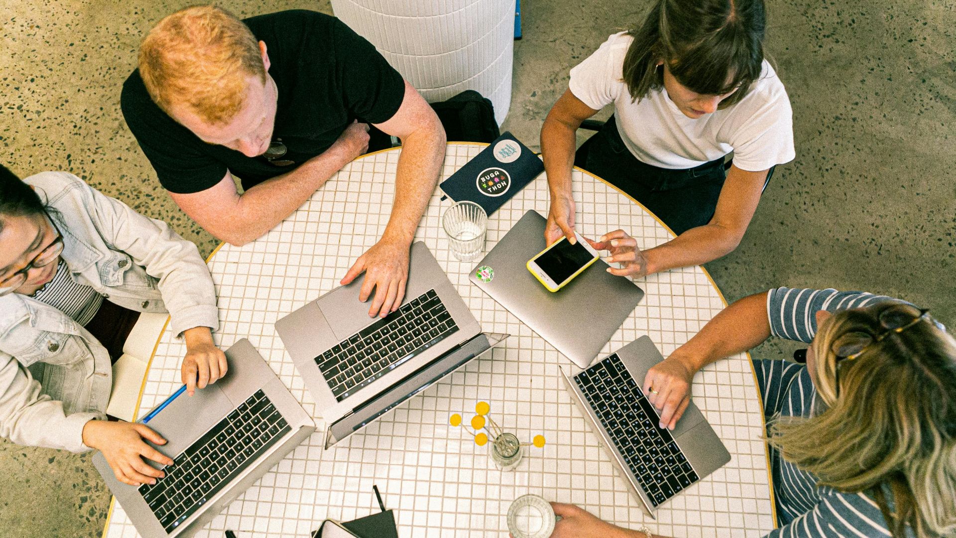 Top view of team collaborating in a modern office around laptops, discussing ideas.