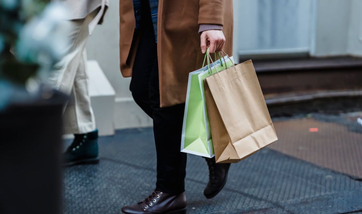 Anonymous woman strolling on street with shopping bags in daytime