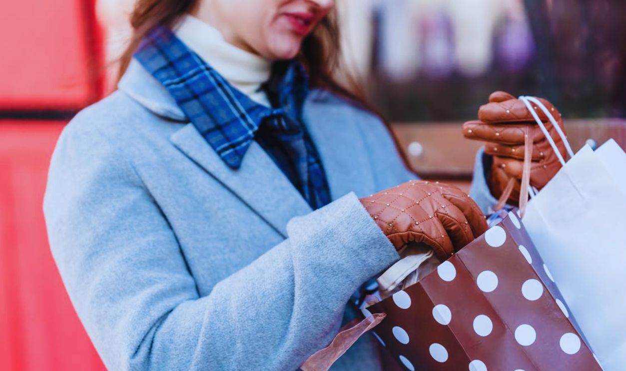 Positive woman with gift packages in street near building