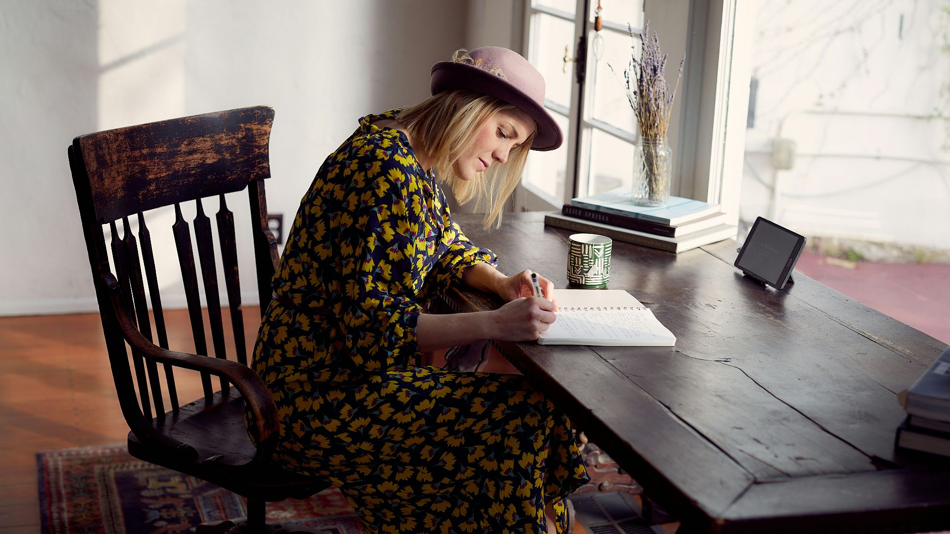 woman in yellow and black floral dress sitting on brown wooden chair