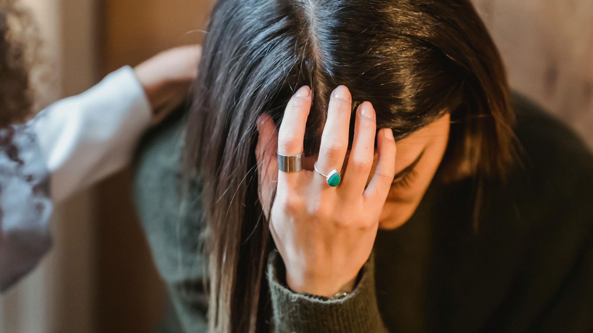 From above of young exhausted sad female in sorrow with supporting crop anonymous friend