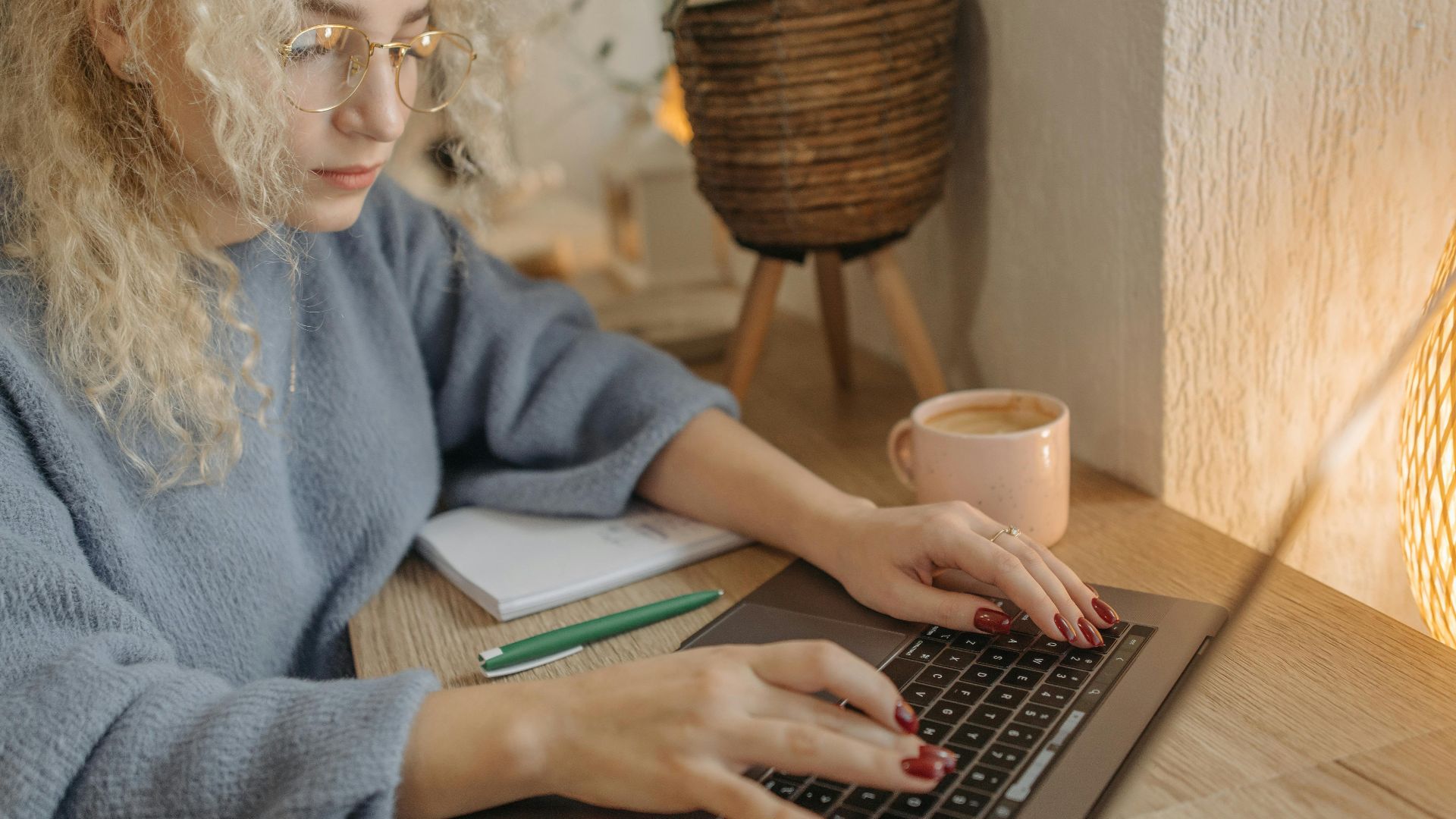 Focused woman with curly hair working on a laptop in a cozy indoor setting.