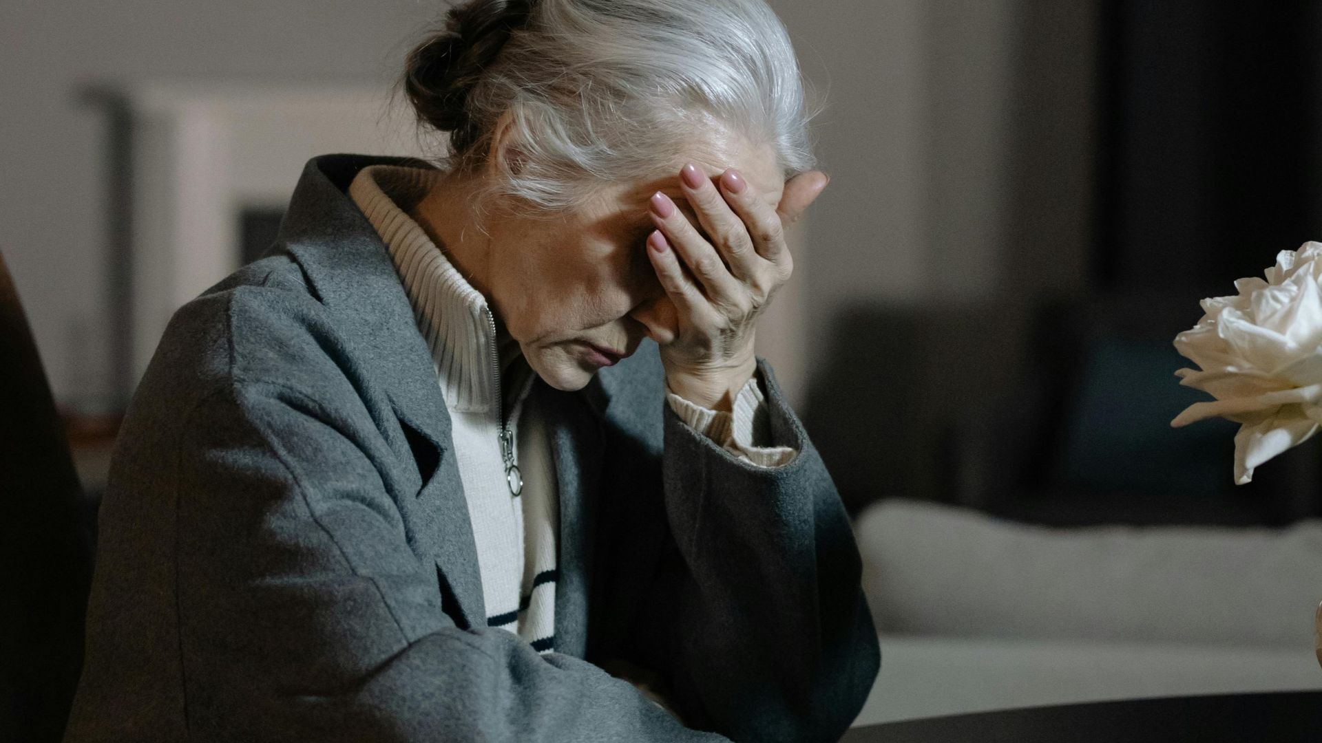 Senior woman grieving indoors at home, expressing deep emotion and loss.