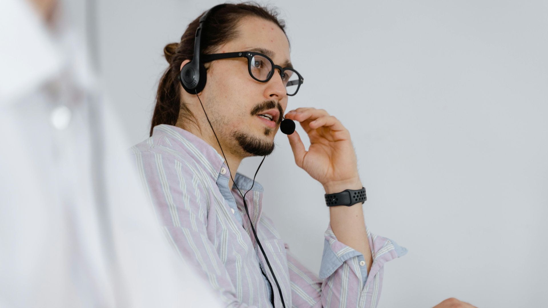 Focused customer service agent speaking on a headset in a modern office environment.