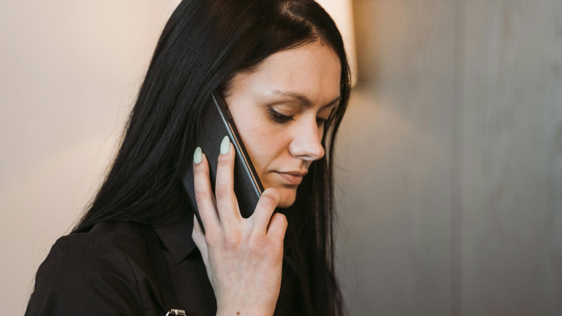Side view of a woman with long hair holding a mobile phone, engaged in conversation.