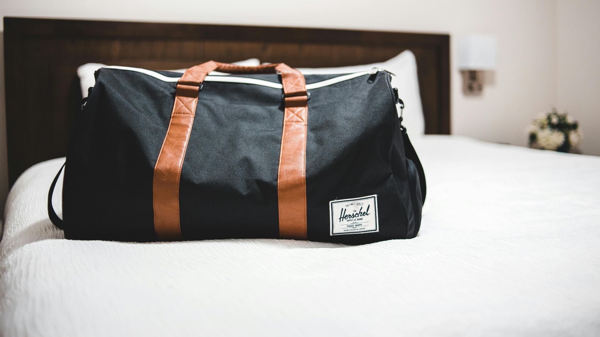 Contemporary baggage bag with inscription on white bed cover in light hotel room