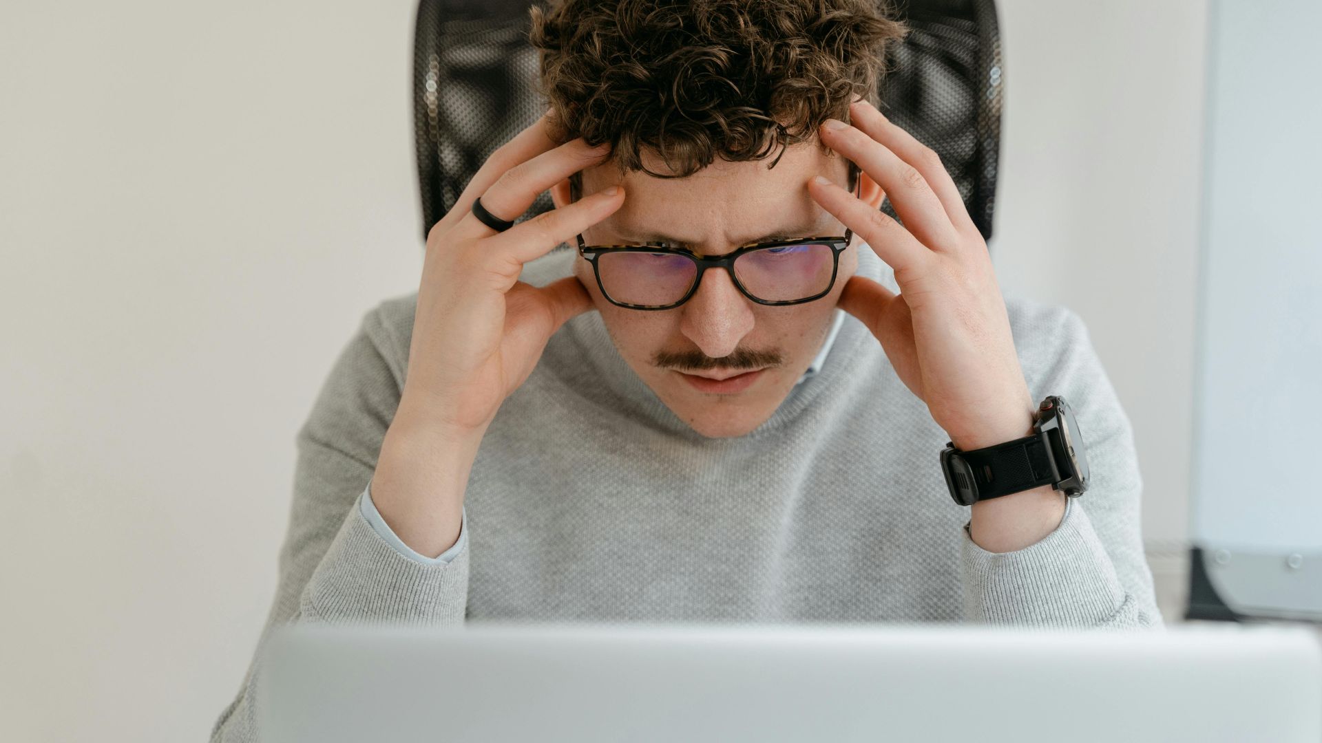 A serious businessman focusing intently on his work, using a laptop indoors.