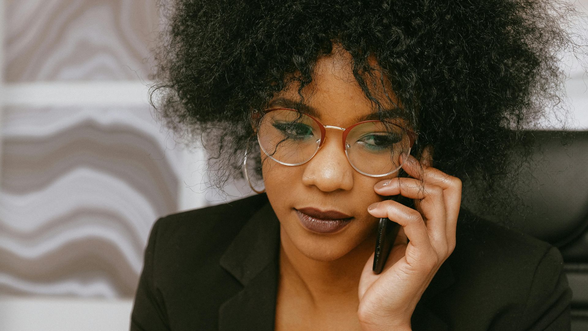 African American businesswoman in office, focused on phone call and tasks.