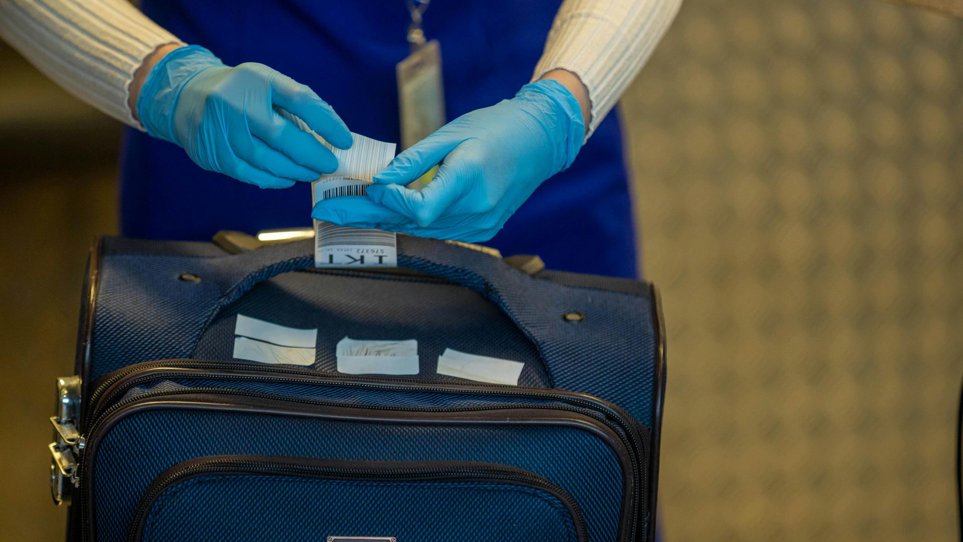 Close-up of airport security process with gloved hands inspecting luggage tags.