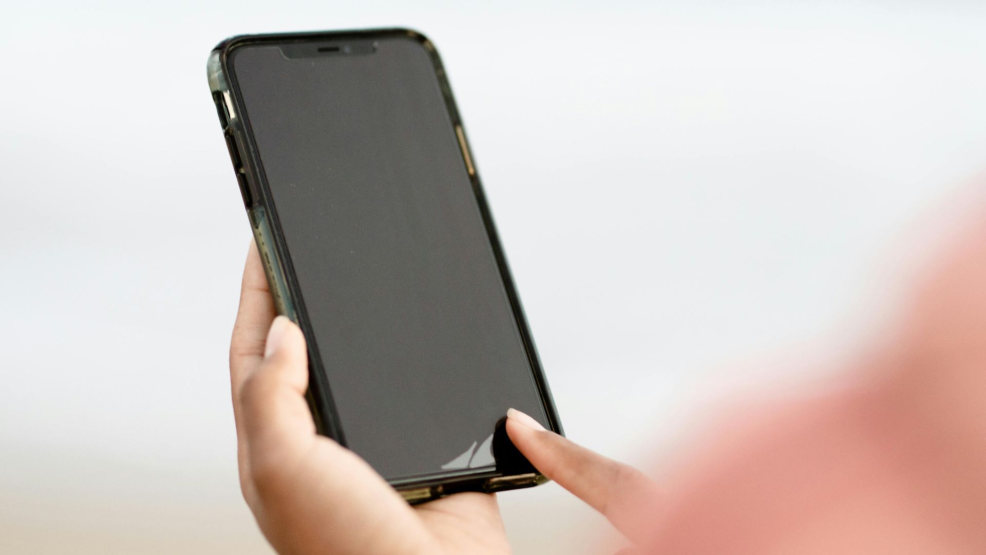 A hand interacting with a smartphone touchscreen outdoors. Modern technology concept.