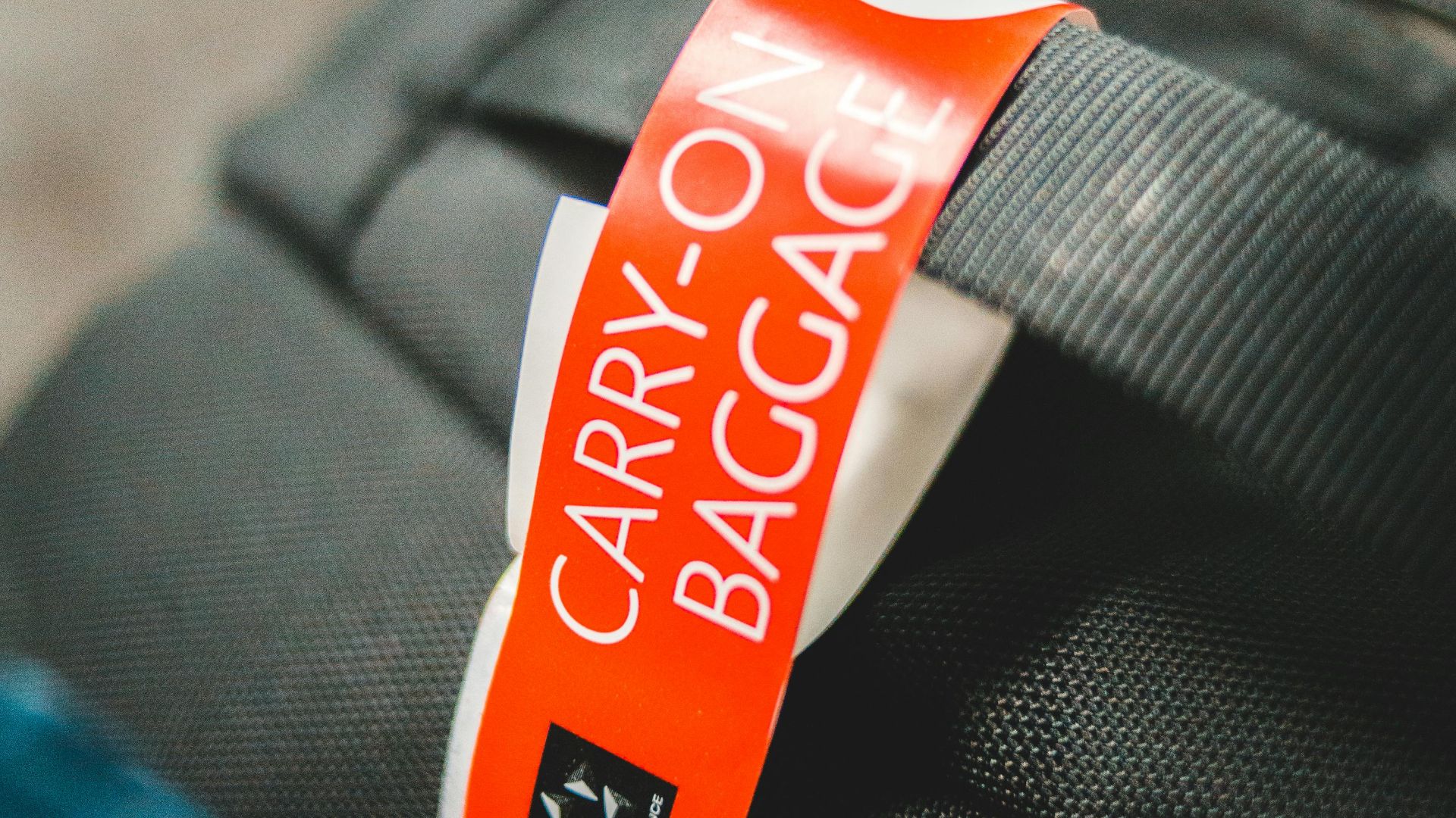 Detailed image of a carry-on baggage tag attached to a gray travel bag, indicating air travel.