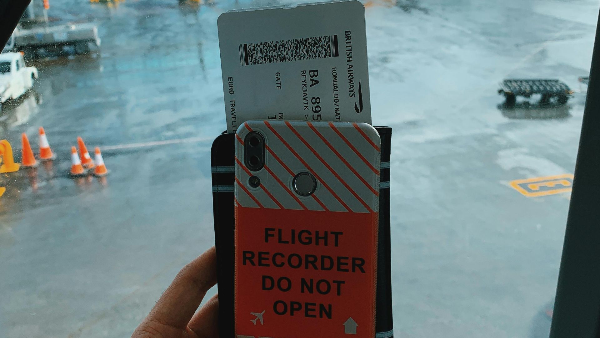 Traveler holding a boarding pass with a plane visible through the window at Keflavík Airport.