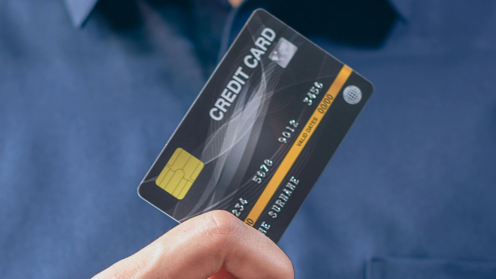 Close-up of a man in a blue shirt holding a credit card, symbolizing finance and security.