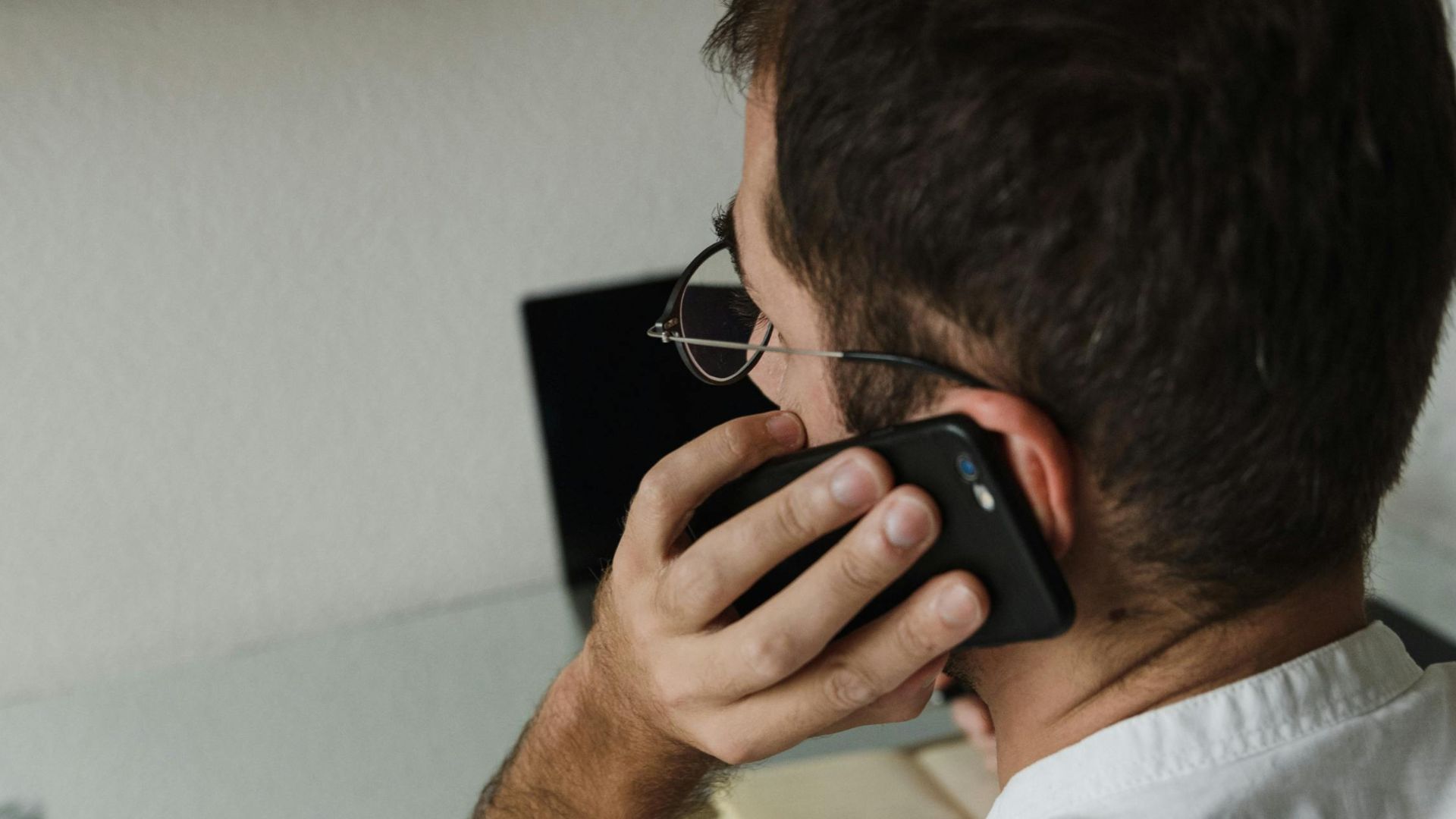 Adult male making a phone call in a minimalist home office setting.