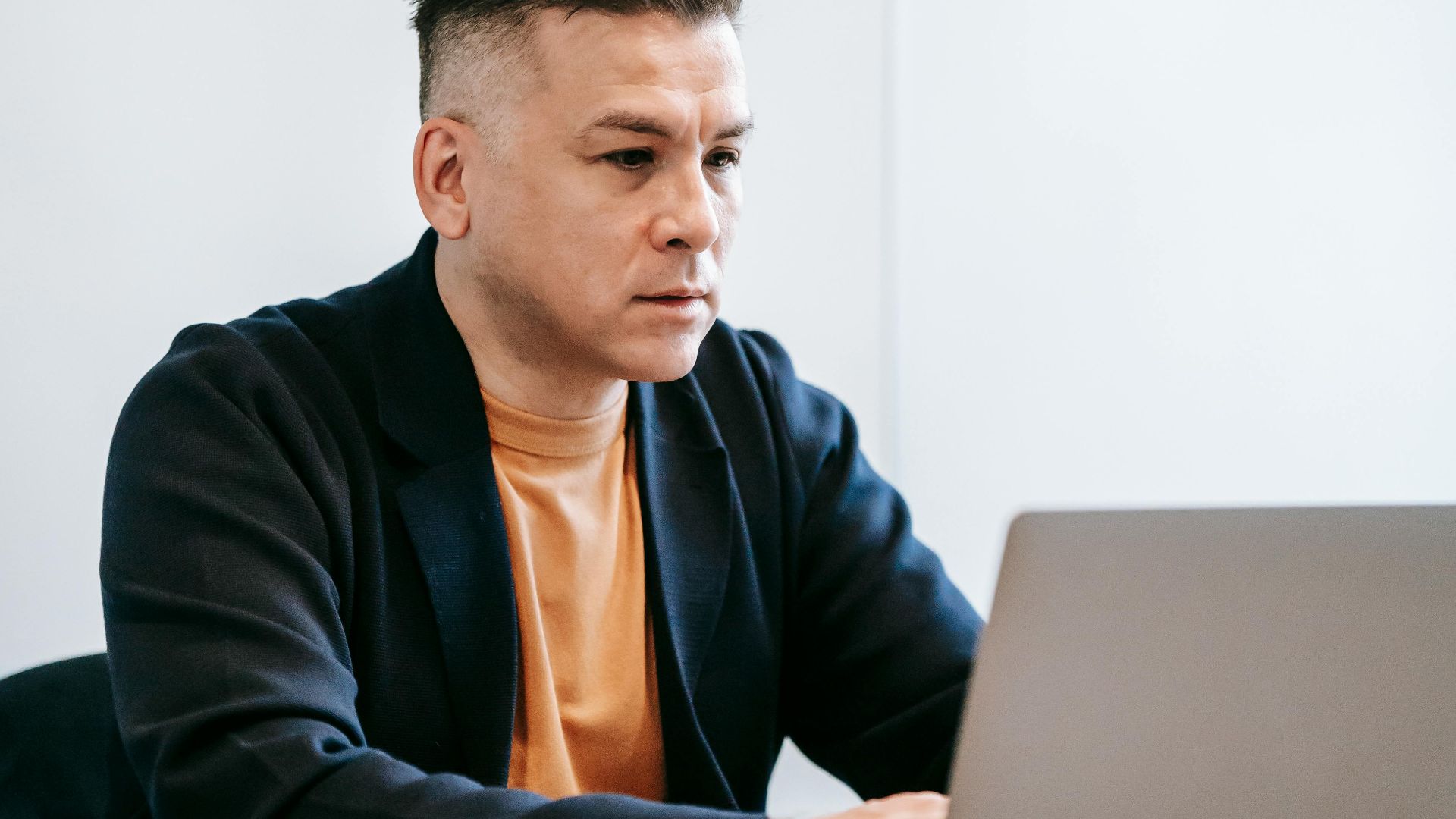Man working intently on a laptop in a modern home office setting.