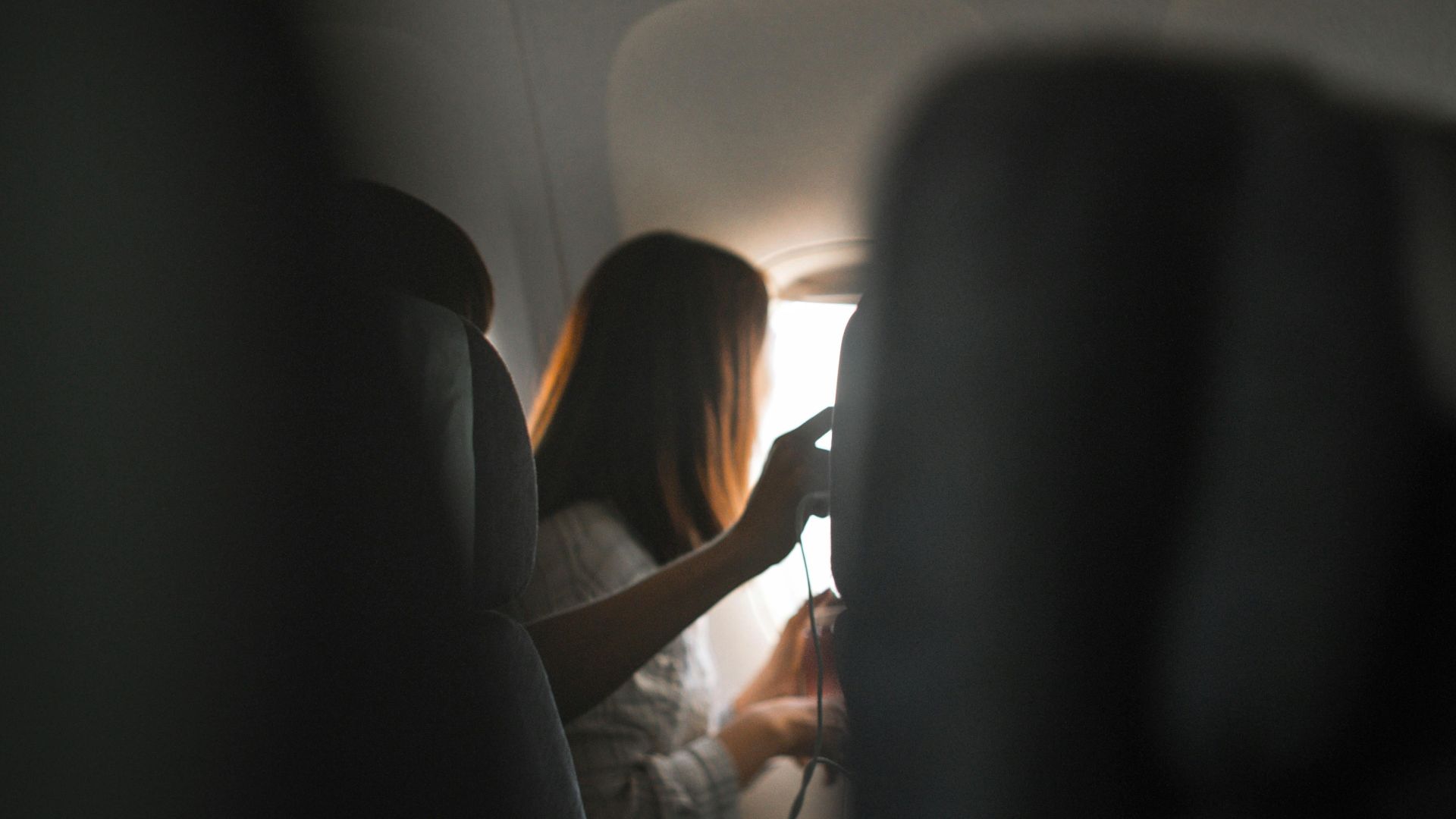 A woman looks out the airplane window, capturing the serene atmosphere of air travel.